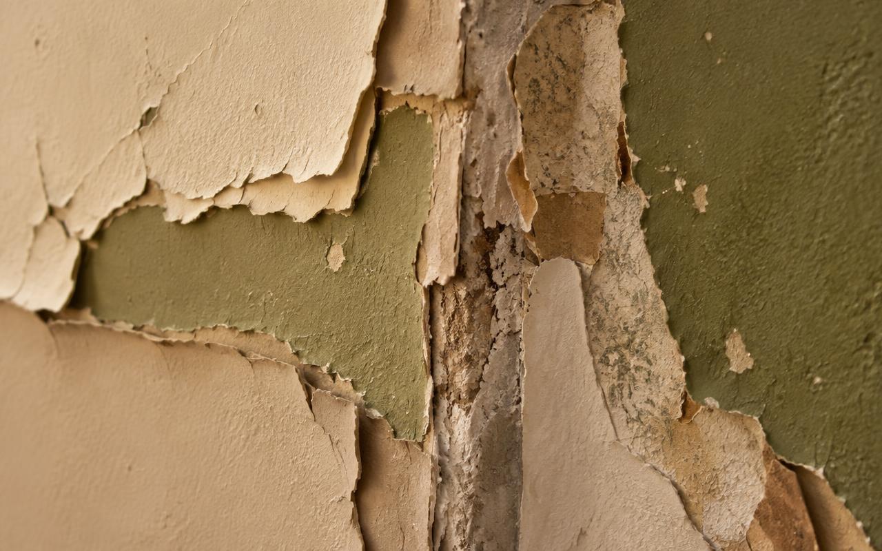 Primer plano de una pared con capas antiguas de pintura y restos de una reforma anterior