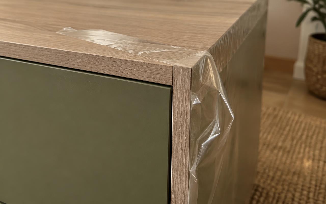 Primer plano de la esquina de un mueble nuevo con plástico protector y cinta de embalaje